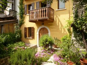 a yellow building with a balcony and flowers at Appartamento vicinanze Vittoriale - Gardone Riviera in Gardone Riviera