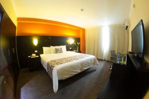 a hotel room with a large bed and a flat screen tv at Hotel El Gran Marqués in Trujillo