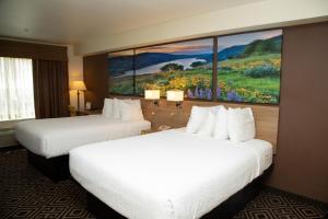 two beds in a hotel room with a painting on the wall at Days Inn by Wyndham Manitou Springs in Manitou Springs