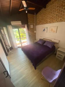 ein Schlafzimmer mit einem lila Bett und einem Fenster in der Unterkunft Casa de 3 Quartos em Garopaba - Bairro Ferraz in Garopaba + 72 Fotos
