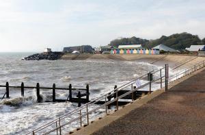 a beach with a fence and waves in the water at Family Marine Apartment with Sea View in Dawlish