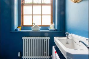 baño con paredes azules, radiador y ventana en Brackenbury House, en Portland