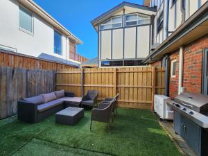 a backyard with a couch and chairs and a grill at On The Beach, Kids & Pets Friendly in Frankston