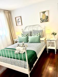 1 dormitorio con cama blanca y almohadas verdes en Apto Céntrico Piscina Garaje Incluido Urbanización, en Castro Urdiales