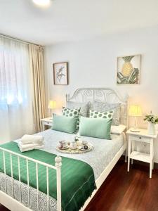 Un dormitorio con una cama blanca con una bandeja de comida. en Apto Céntrico Piscina Garaje Incluido Urbanización, en Castro Urdiales