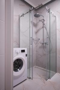a washing machine in a bathroom with a shower at Riverside Dziwnów Apartament i SPA in Dziwnów