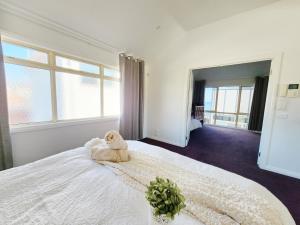a teddy bear sitting on a bed in a bedroom at On The Beach, Kids & Pets Friendly in Frankston