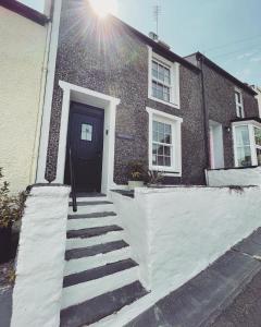 een stenen huis met een zwarte deur en een trap bij Bryn Goleu, Mersey Street, Borth-y-Gest in Porthmadog