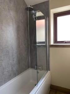 a shower with a glass door in a bathroom at Wagtail Cottage in Cloughton