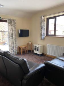 a living room with a couch and a television at Wagtail Cottage in Cloughton