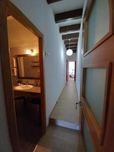 einen Flur, der zu einem Bad mit einem Waschbecken und einem Spiegel führt in der Unterkunft Casa Rosita in Les Cases d'Alcanar