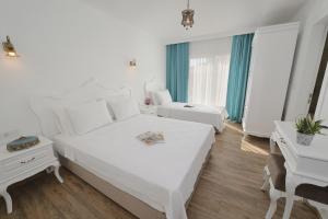 a white bedroom with two beds and a desk at Alesya Otel in Çiftlikköyü +16 photos