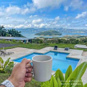 a person holding a cup in front of a pool at Casa Felipe, lake view-cottage in Nuevo Arenal