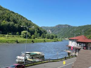 a boat is docked next to a building on a river at Pension Jitřenka Hřensko in Hřensko