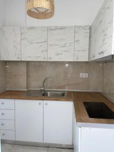 a kitchen with white cabinets and a sink at Athena's Studios 2 in Polykhrono