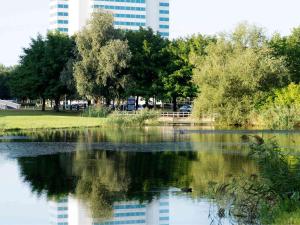 uitzicht op een vijver in een park met een gebouw bij Novotel Rotterdam Brainpark in Rotterdam