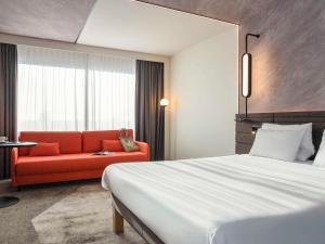 Habitación de hotel con cama y sofá rojo en Novotel Rotterdam Brainpark en Róterdam