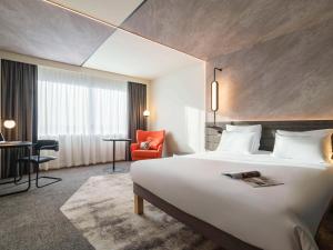 um quarto de hotel com uma cama grande e uma cadeira vermelha em Novotel Rotterdam Brainpark em Roterdã