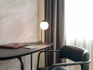 a desk with a lamp and a chair next to a window at Novotel Rotterdam Brainpark in Rotterdam