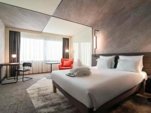 Cette chambre d'hôtel comprend un grand lit et un fauteuil rouge. dans l'établissement Novotel Rotterdam Brainpark, à Rotterdam