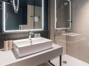 La salle de bains est pourvue d'un lavabo blanc et d'une douche. dans l'établissement Novotel Rotterdam Brainpark, à Rotterdam