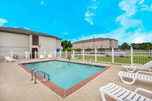 - une piscine avec des chaises et une clôture blanche dans l'établissement Motel 6-Abbeville, LA, à Abbeville