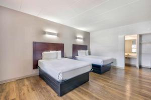a hotel room with two beds and wooden floors at Motel 6-Falls Church, VA - Arlington Boulevard in Falls Church