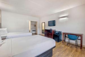 a hotel room with two beds and a desk and a tv at Motel 6-Falls Church, VA - Arlington Boulevard in Falls Church