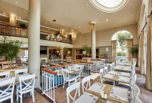 un restaurante con mesas blancas y sillas blancas en StayEasy Century City en Ciudad del Cabo