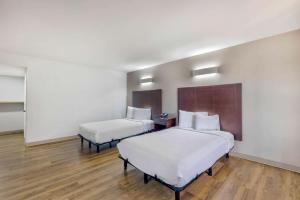 two beds in a room with white walls and wooden floors at Motel 6-Falls Church, VA - Arlington Boulevard in Falls Church