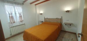 uma cama laranja num quarto branco com uma janela em ALOJAMIENTOS EL CASTRO em Taramundi