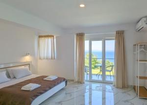 een slaapkamer met een bed en uitzicht op de oceaan bij Blue Dream Afytos in Afitos