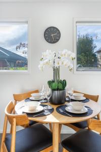 mesa de comedor con sillas y reloj en la pared en 2 bed Escape, Heart of Riccarton w/carpark en Christchurch