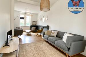 uma sala de estar com um sofá cinzento e uma televisão em L'Authentique maison cosy et rénovée em Condat-sur-Vienne