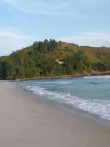 a beach with a house on top of a hill at Ohana's Flat Maresias in São Sebastião