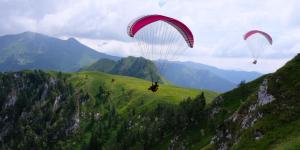 two paragliders are flying over a mountain at Gaya Residences in Shahdag