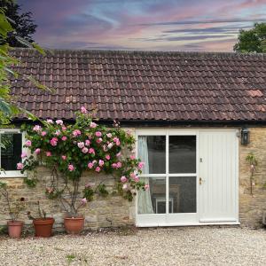 a house with a window and a bush with pink roses at Whitley Coach House in Whitley