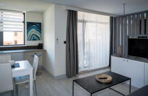a living room with a tv and a table and a kitchen at ADIRAMA Apartments Elegant Apartments Walk to the Beach in Obzor