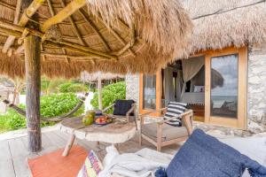 a patio with a table and a straw hut at Ahau Tulum in Tulum