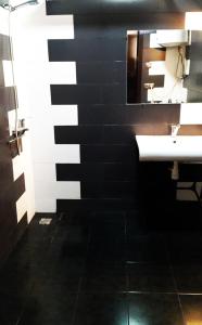 a black and white bathroom with a sink and a mirror at Eka Guest House in Batumi