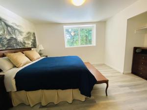 a bedroom with a large bed with a blue blanket at The Rhodo Place in Coquitlam