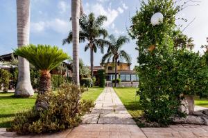 a walkway in front of a house with palm trees at Valleforno Country House di Charme in Ispica