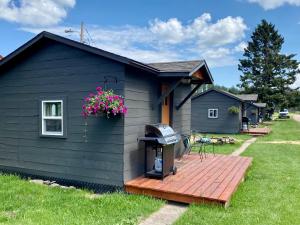 a black house with a grill on a deck at Cabin 7 at Horse Creek Resort in Rapid City