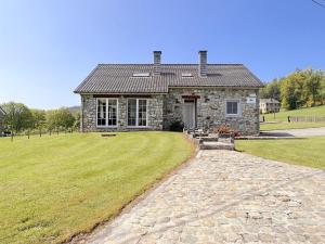 a stone house with a grassy yard in front of it at Bra de Pierre in Lierneux