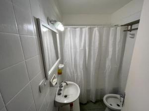 Baño blanco con lavabo y aseo en Confortable Departamento en Palermo Soho en Buenos Aires
