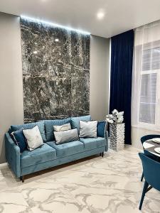 eine blaue Couch in einem Wohnzimmer mit einem Gemälde in der Unterkunft Family Residence Boutique Apartments in Lwiw