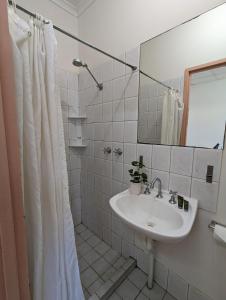 uma casa de banho branca com um lavatório e um espelho em Studio 18 Wright Lodge em Adelaide