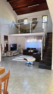 a living room with a couch and a stair case at Casa com piscina em boraceia a 400 metros da praia in Boracéia