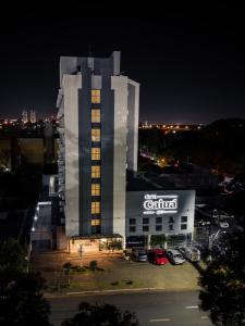 um edifício iluminado com um concessionário de carros à noite em Hotel Caiuá Express em Maringá