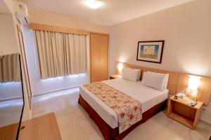 a hotel room with a bed and a window at Hotsprings Suite Hotel in Caldas Novas